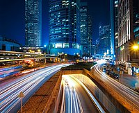 Nachtaufnahme einer Straße. Die Lichter der Autos erscheinen als Streifen über das ganze Bild.