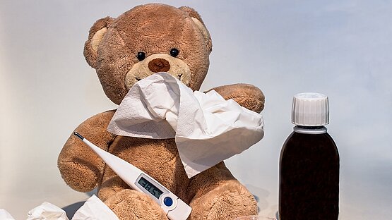 Kranker Teddybär mit Fieberthermometer Taschentüchern und Medizin
