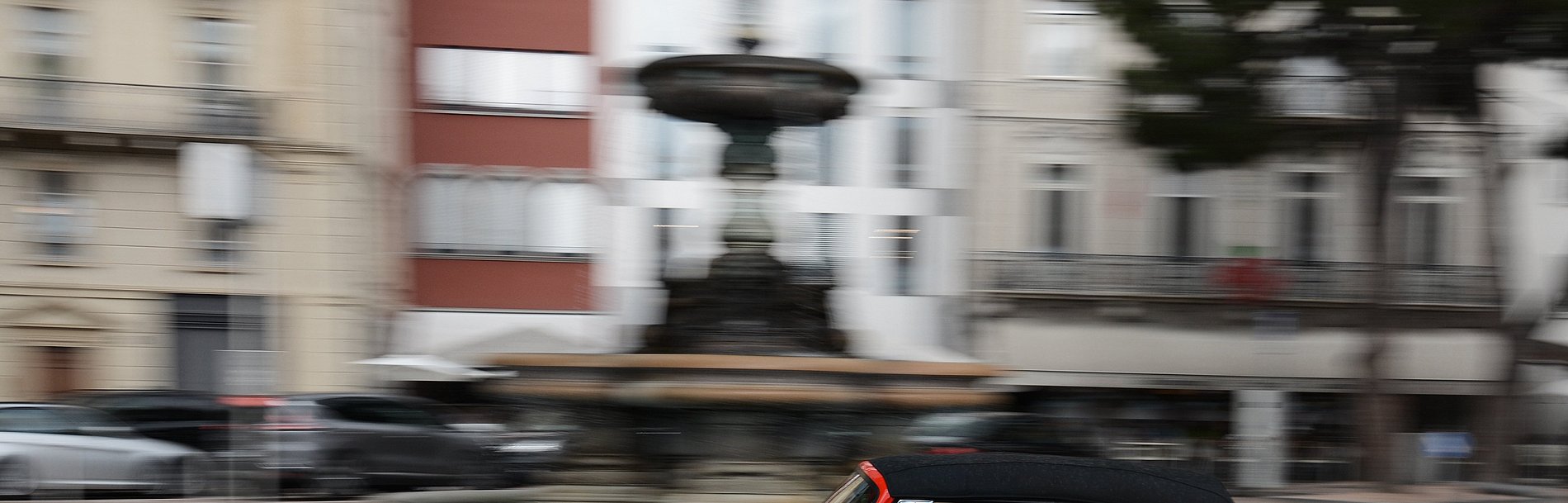 Roter VW Käfer fährt vor unscharfem Hintergund