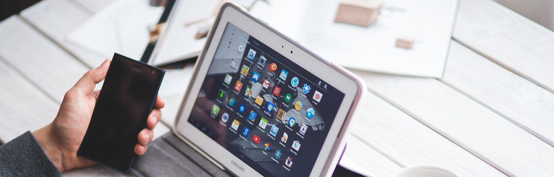 Mann sitzt am Tisch mit Tablet Handy und einer Tasse Kaffee