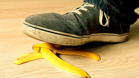 Fuß, der auf eine Bananenschale tritt und droht, auszurutschen.