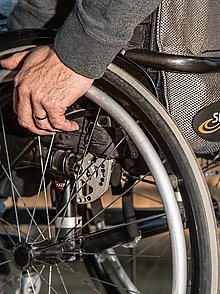 Seitliche Detailaufnahme eines Rollstuhls. Teil der Räder und des Sitzes.