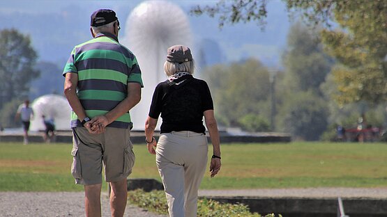 Älteres Paar von hinten spaziert durch einen Park