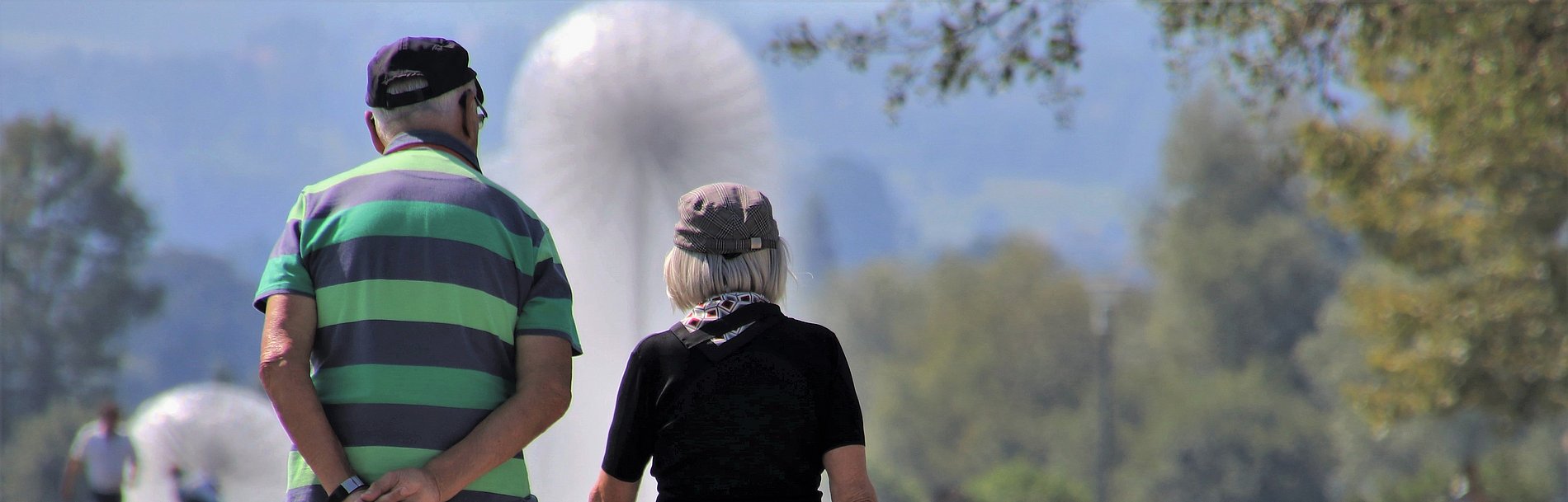 Älteres Paar von hinten spaziert durch einen Park
