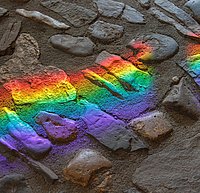 Regenbogenartige Lichtreflexion auf dunklem Steinboden